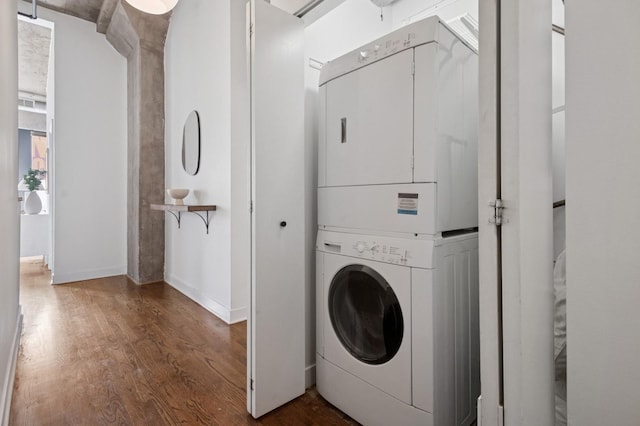 washroom with laundry area, stacked washer and clothes dryer, and wood finished floors