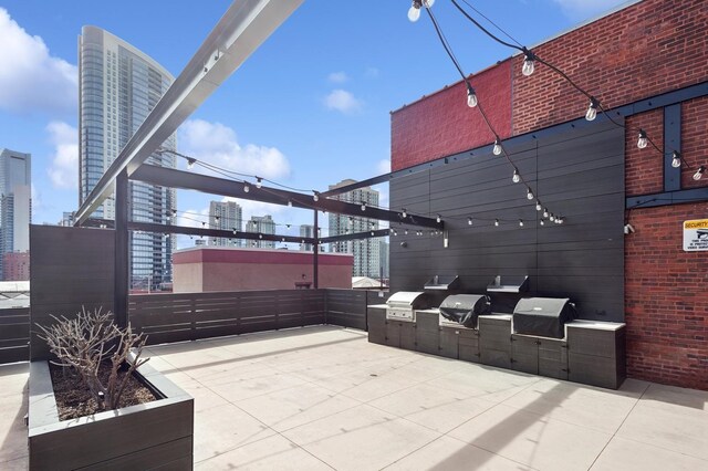 view of patio with area for grilling, a view of city, and exterior kitchen