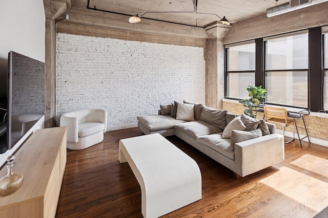 living room with wood finished floors and brick wall