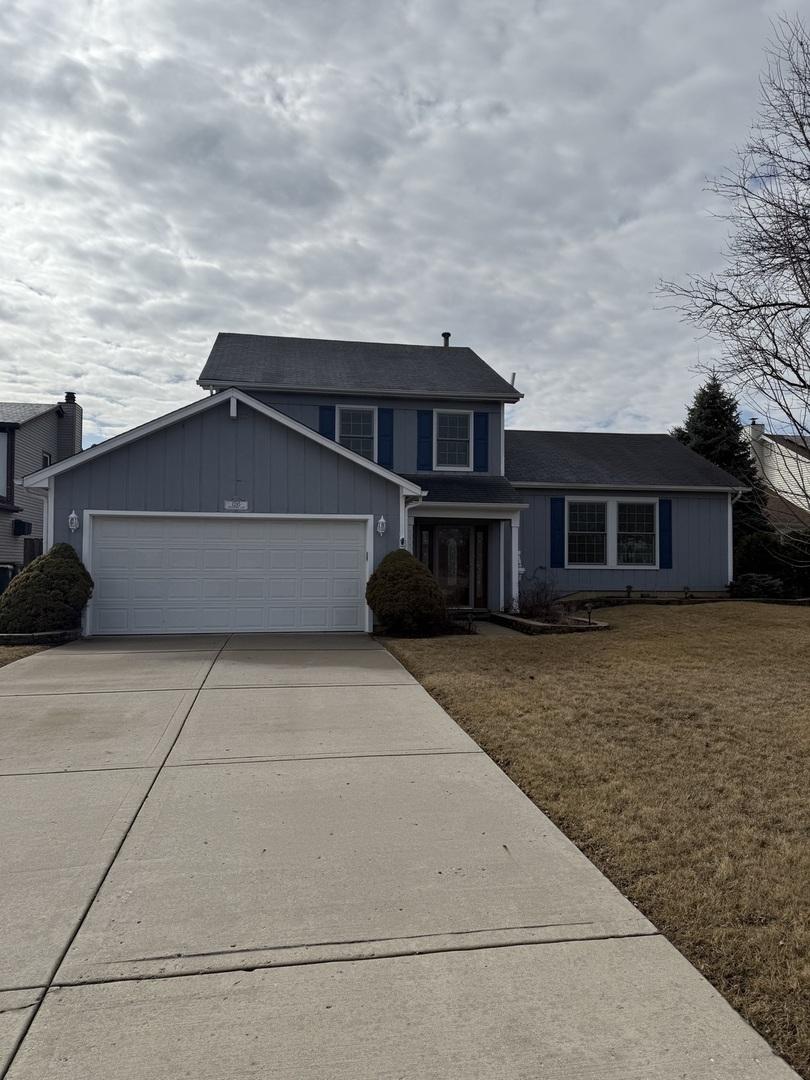 traditional home featuring concrete driveway, an attached garage, and a front yard