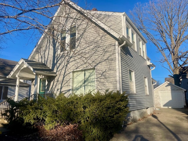 view of side of home with an outbuilding, a detached garage, and driveway