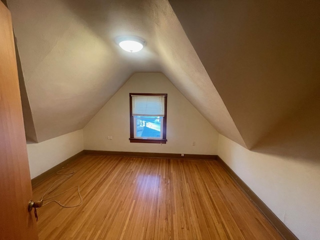 bonus room with lofted ceiling, baseboards, and wood finished floors