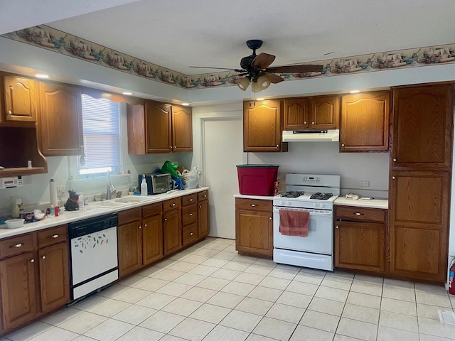 kitchen with white appliances, light countertops, under cabinet range hood, and a sink