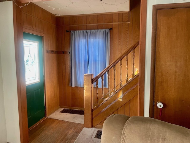 foyer entrance featuring stairway, wood walls, and wood finished floors