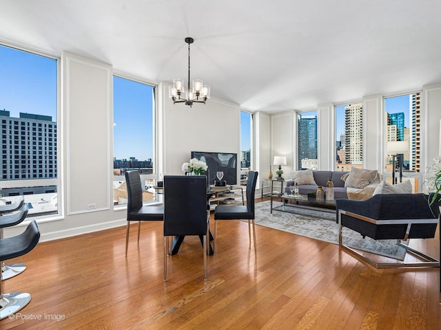 dining space featuring baseboards, a wall of windows, an inviting chandelier, and wood-type flooring