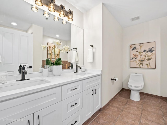 bathroom featuring a sink, visible vents, toilet, and double vanity