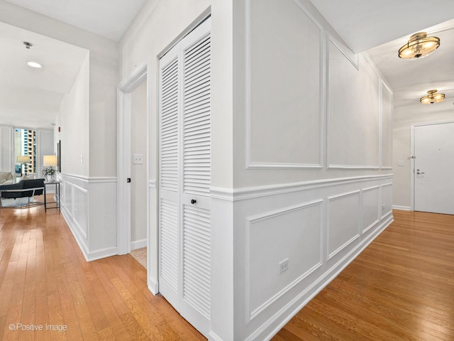 hallway featuring light wood-style floors and a decorative wall