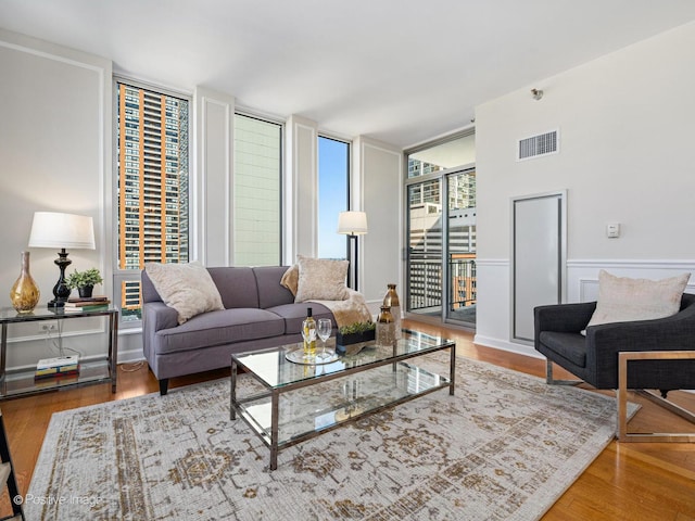 living area featuring visible vents, wainscoting, and wood finished floors