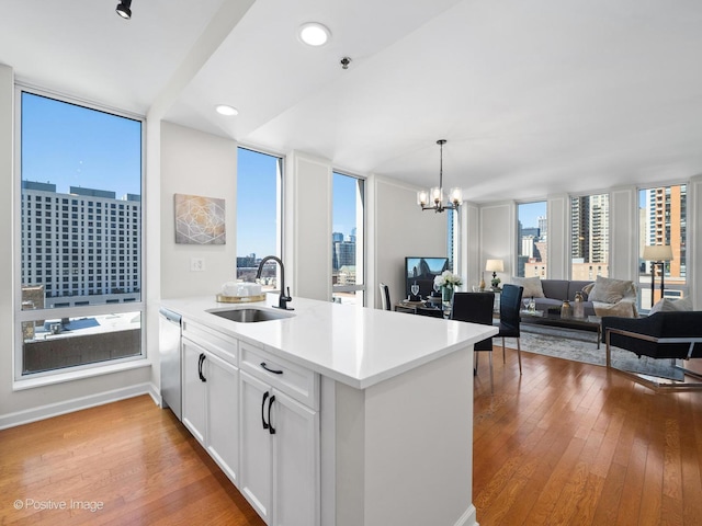 kitchen with a sink, expansive windows, light wood-type flooring, and a peninsula