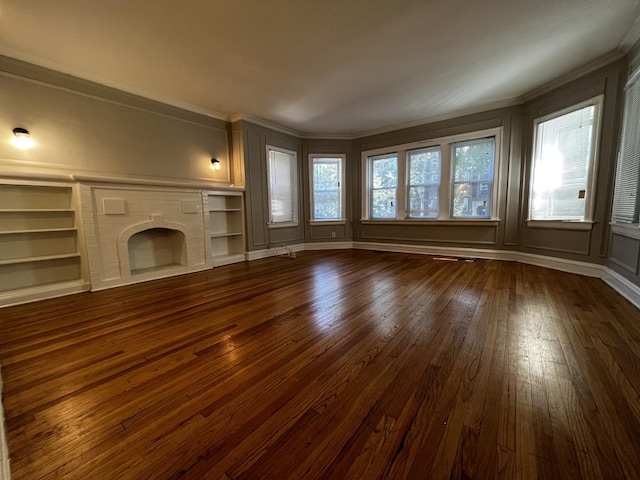 unfurnished living room with dark wood-type flooring, crown molding, built in features, a fireplace, and a decorative wall