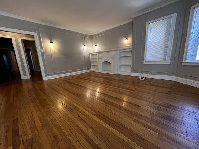 unfurnished living room featuring dark wood-style floors, a decorative wall, a fireplace, and crown molding