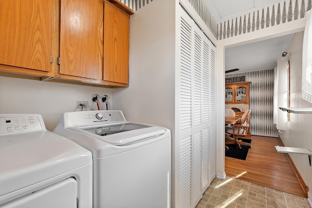 clothes washing area featuring cabinet space and independent washer and dryer