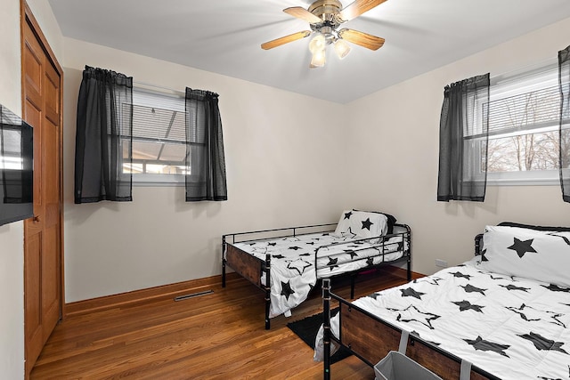 bedroom featuring visible vents, baseboards, wood finished floors, a closet, and a ceiling fan