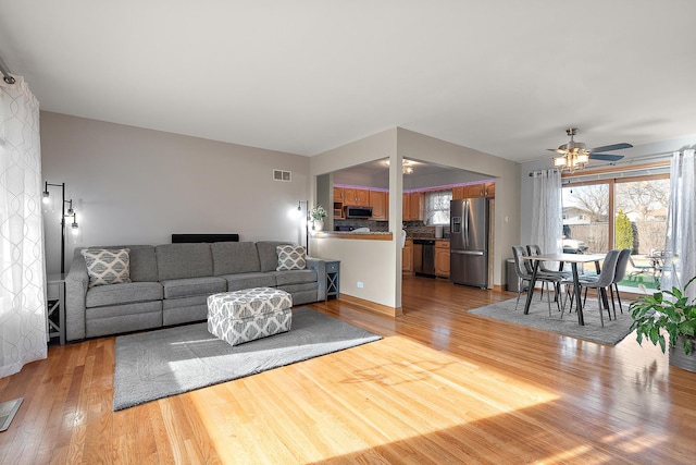 living area with light wood-style flooring, a ceiling fan, and visible vents