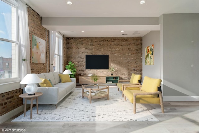 living area featuring brick wall and wood finished floors