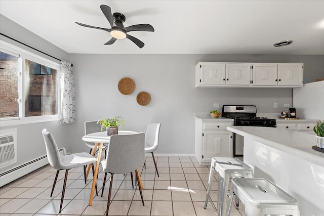 kitchen with a ceiling fan, light tile patterned flooring, light countertops, white cabinets, and stainless steel gas stove