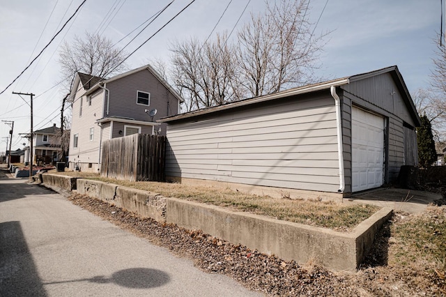 view of property exterior featuring an outbuilding, fence, and a garage