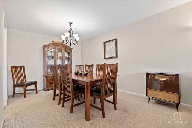 dining area with a notable chandelier, light colored carpet, and baseboards