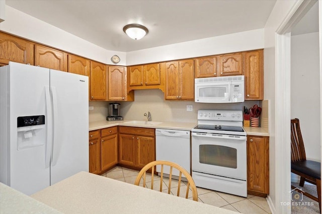 kitchen featuring a sink, white appliances, brown cabinets, and light tile patterned floors