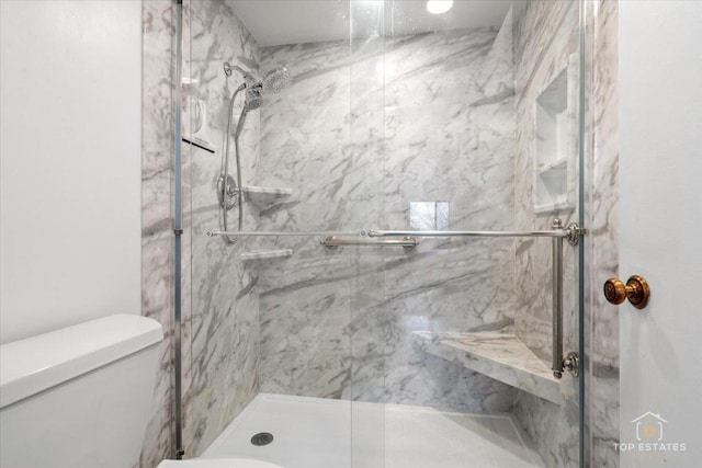 bathroom featuring a marble finish shower and toilet