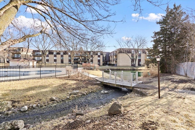 exterior space with a residential view, a community pool, and fence