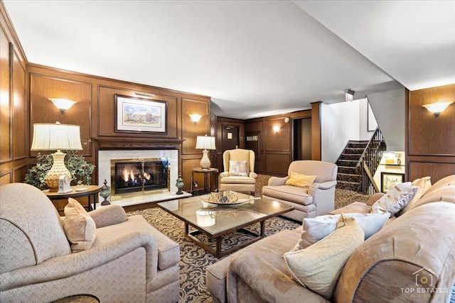 living room featuring stairs, a decorative wall, and a high end fireplace