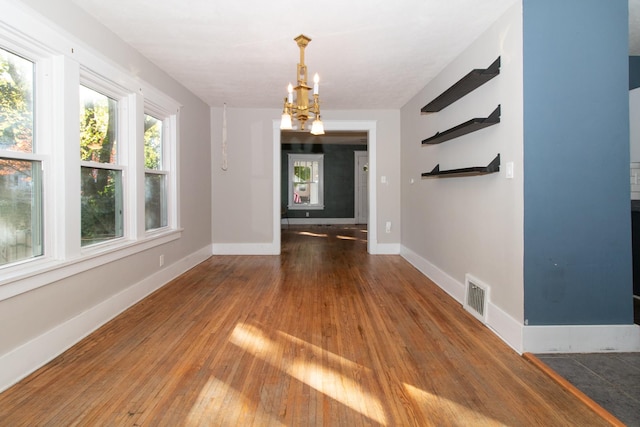 interior space with a chandelier, visible vents, baseboards, and wood-type flooring