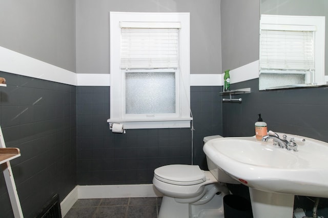 bathroom featuring tile patterned floors, visible vents, toilet, a sink, and tile walls