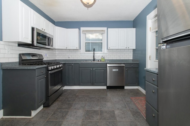 kitchen with a sink, dark countertops, gray cabinetry, and stainless steel appliances