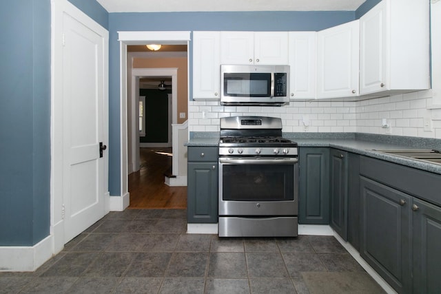 kitchen with stainless steel appliances, backsplash, gray cabinets, and white cabinetry