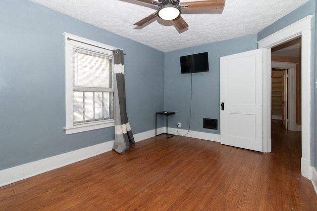 unfurnished room with visible vents, baseboards, wood finished floors, a textured ceiling, and a ceiling fan