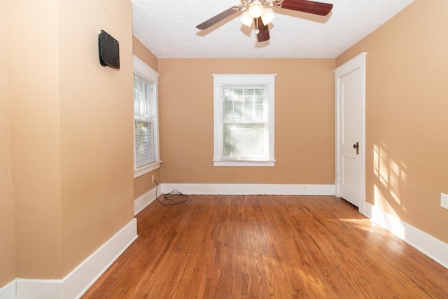 spare room featuring a textured ceiling, baseboards, and wood finished floors