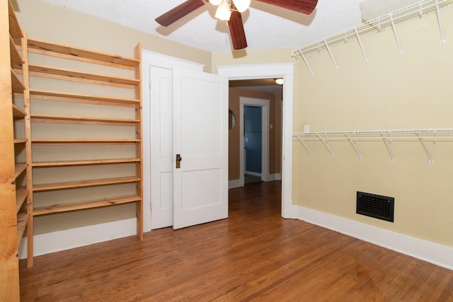 interior space featuring wood finished floors, visible vents, and ceiling fan