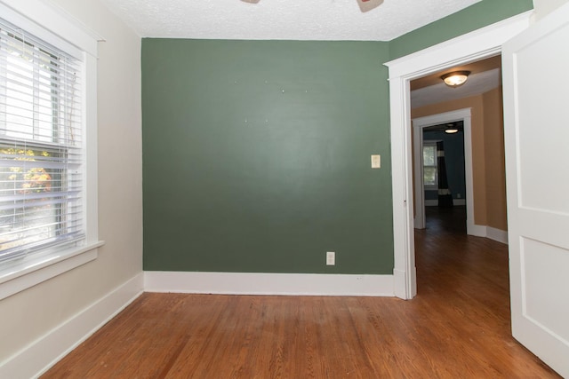 unfurnished room with baseboards, a textured ceiling, wood finished floors, and a ceiling fan