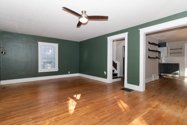 interior space featuring visible vents, wood finished floors, stairway, a fireplace, and baseboards