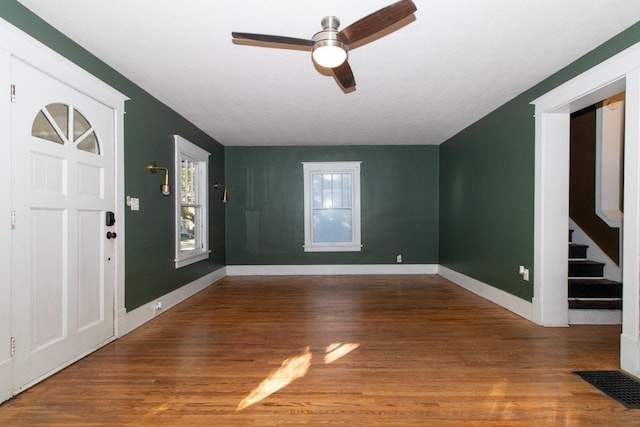 entryway with stairs, wood finished floors, visible vents, and baseboards