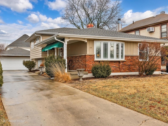 view of front of property with brick siding, a chimney, a wall mounted AC, and a garage