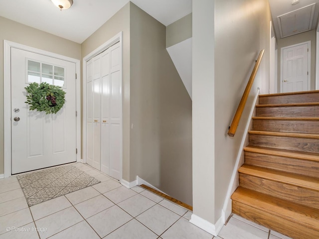 entryway with light tile patterned floors, stairway, and baseboards