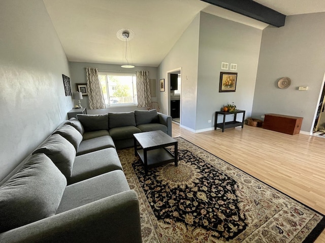 living area with light wood finished floors, beam ceiling, high vaulted ceiling, and baseboards