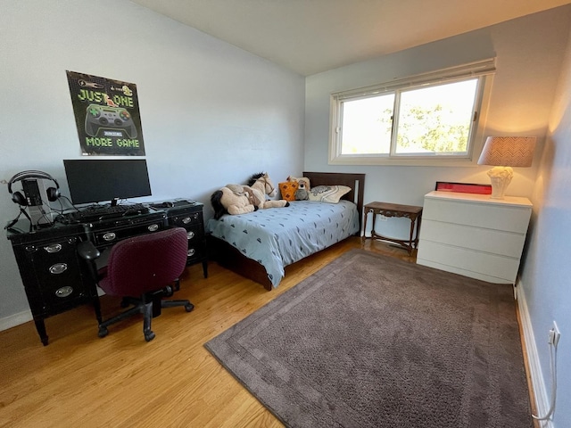 bedroom with lofted ceiling and light wood-style floors