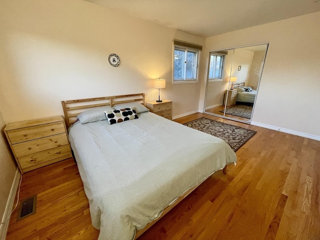 bedroom with visible vents, baseboards, a closet, and wood finished floors