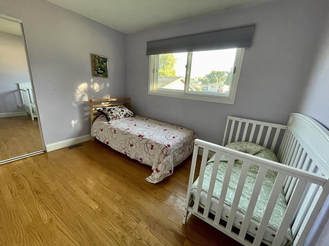 bedroom featuring visible vents, baseboards, and wood finished floors