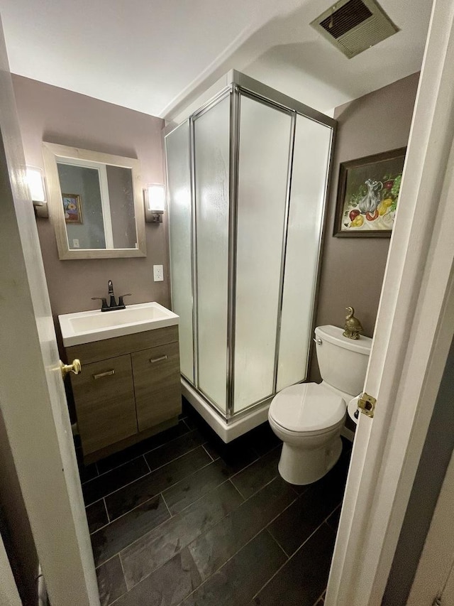 bathroom with visible vents, a shower stall, vanity, and toilet