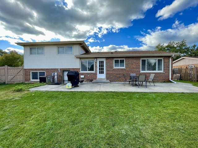 rear view of house with a patio, brick siding, a lawn, and fence