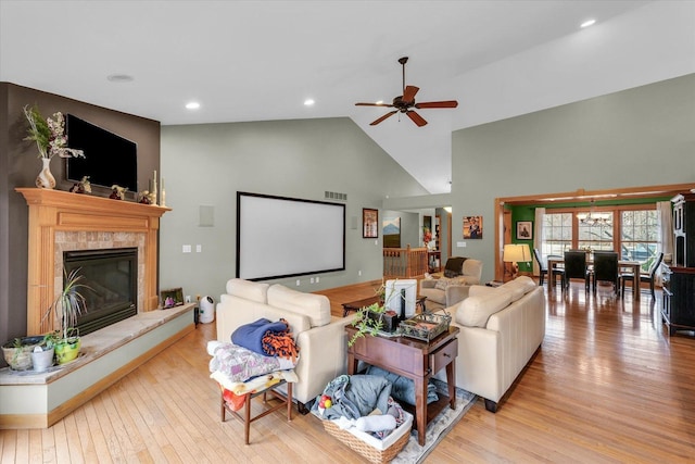 living room with a ceiling fan, visible vents, high vaulted ceiling, a fireplace, and wood-type flooring