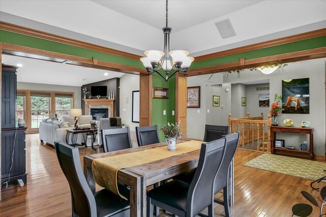 dining space with visible vents, a notable chandelier, a glass covered fireplace, hardwood / wood-style floors, and recessed lighting