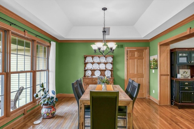 dining space with visible vents, baseboards, light wood-type flooring, a tray ceiling, and an inviting chandelier