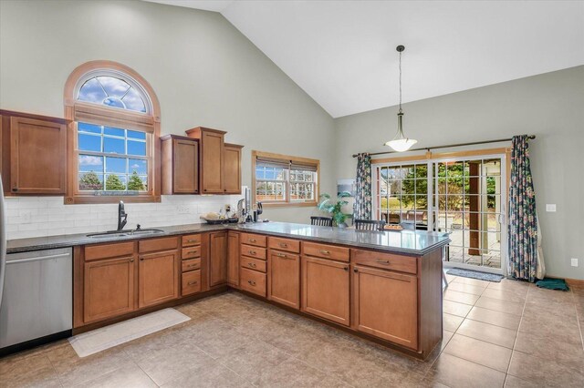 kitchen featuring dark countertops, dishwasher, brown cabinets, a peninsula, and a sink