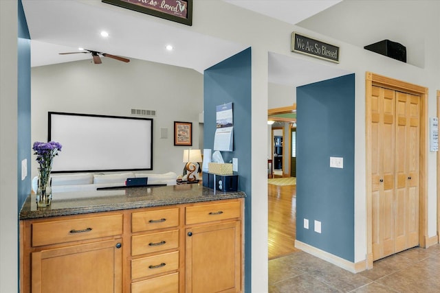 kitchen featuring visible vents, open floor plan, vaulted ceiling, dark stone countertops, and light tile patterned flooring