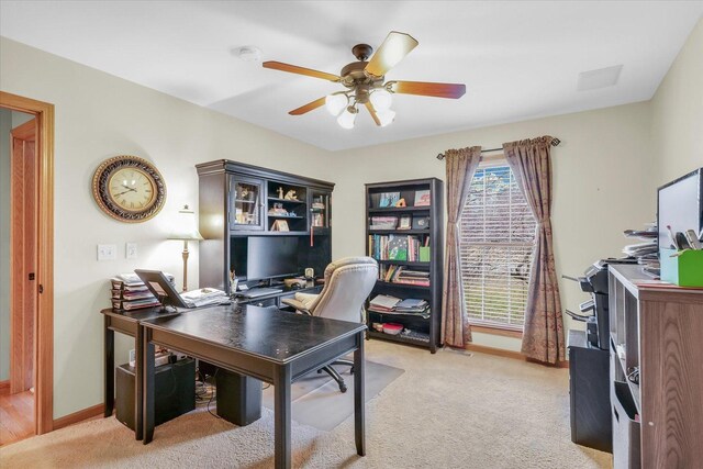 office featuring baseboards, light colored carpet, and a ceiling fan